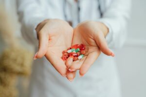 A close-up image of female hands holding diverse colorful pills and capsules.